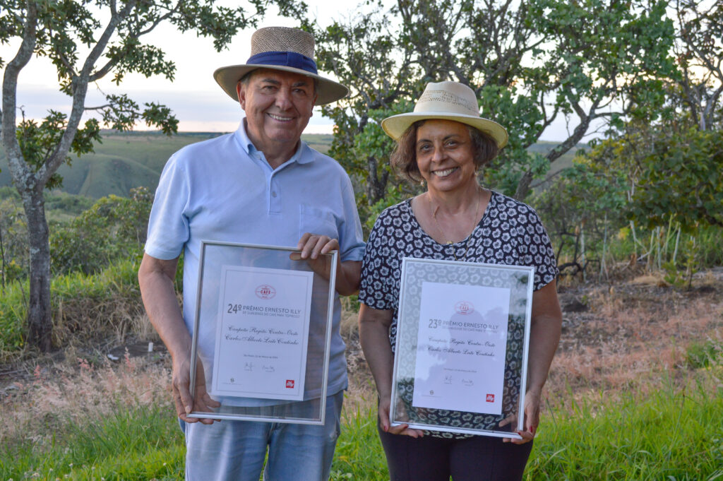 _DSC0190-3 Duas pessoas segurando certificados de premiação em uma área rural