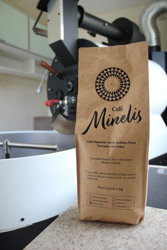 Pacote de café Café Minelis diante de um torrador